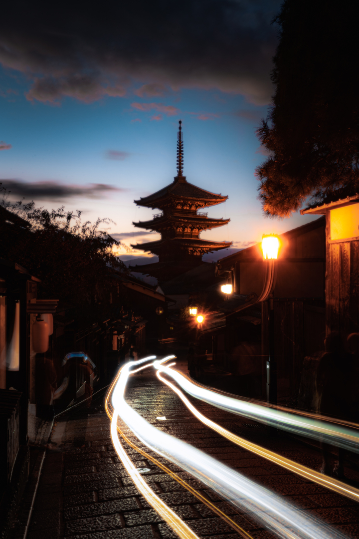 light trails under a pagoda at sunset